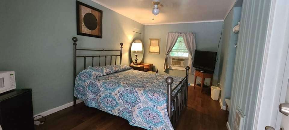 Light guest room with wood bed frame and blue quilt