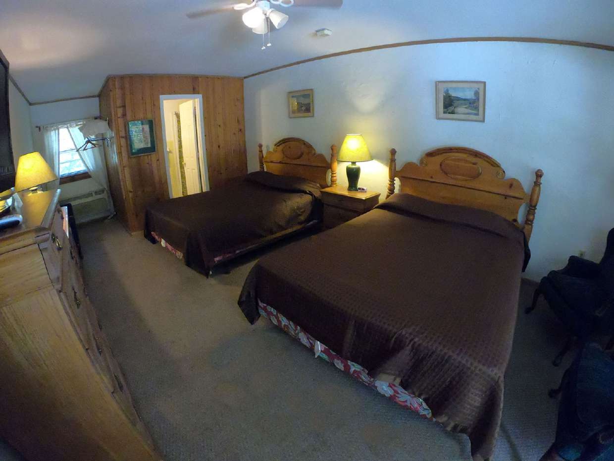 Two queen beds in a wood-paneled room