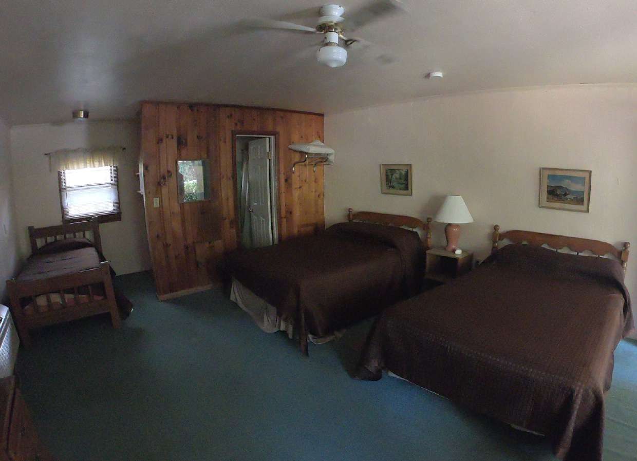 Wood-paneled room with two queen beds and ceiling fan