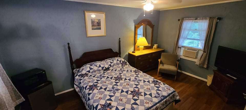 Deep blue guest room with dresser and window