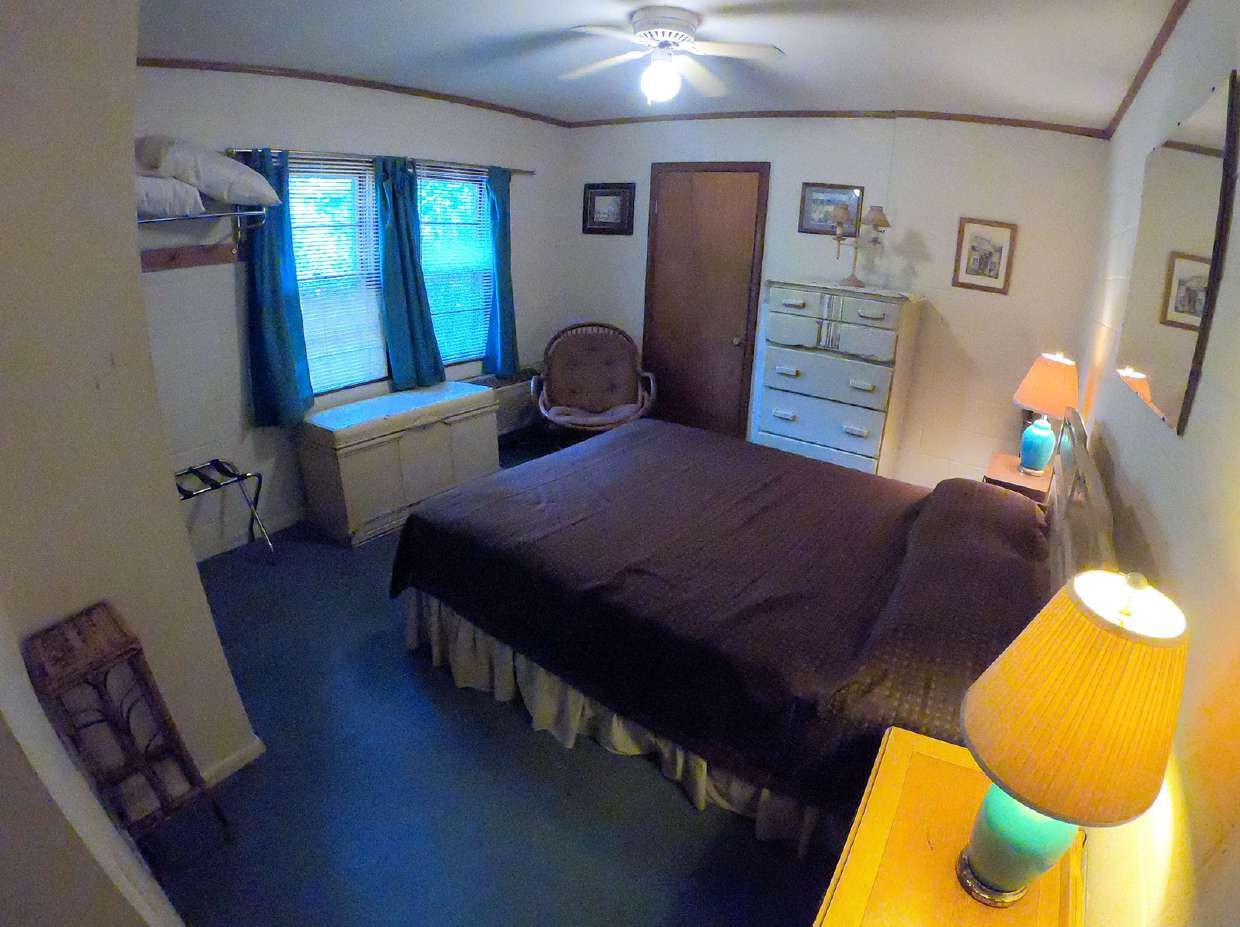 Queen bed beside a sunny window