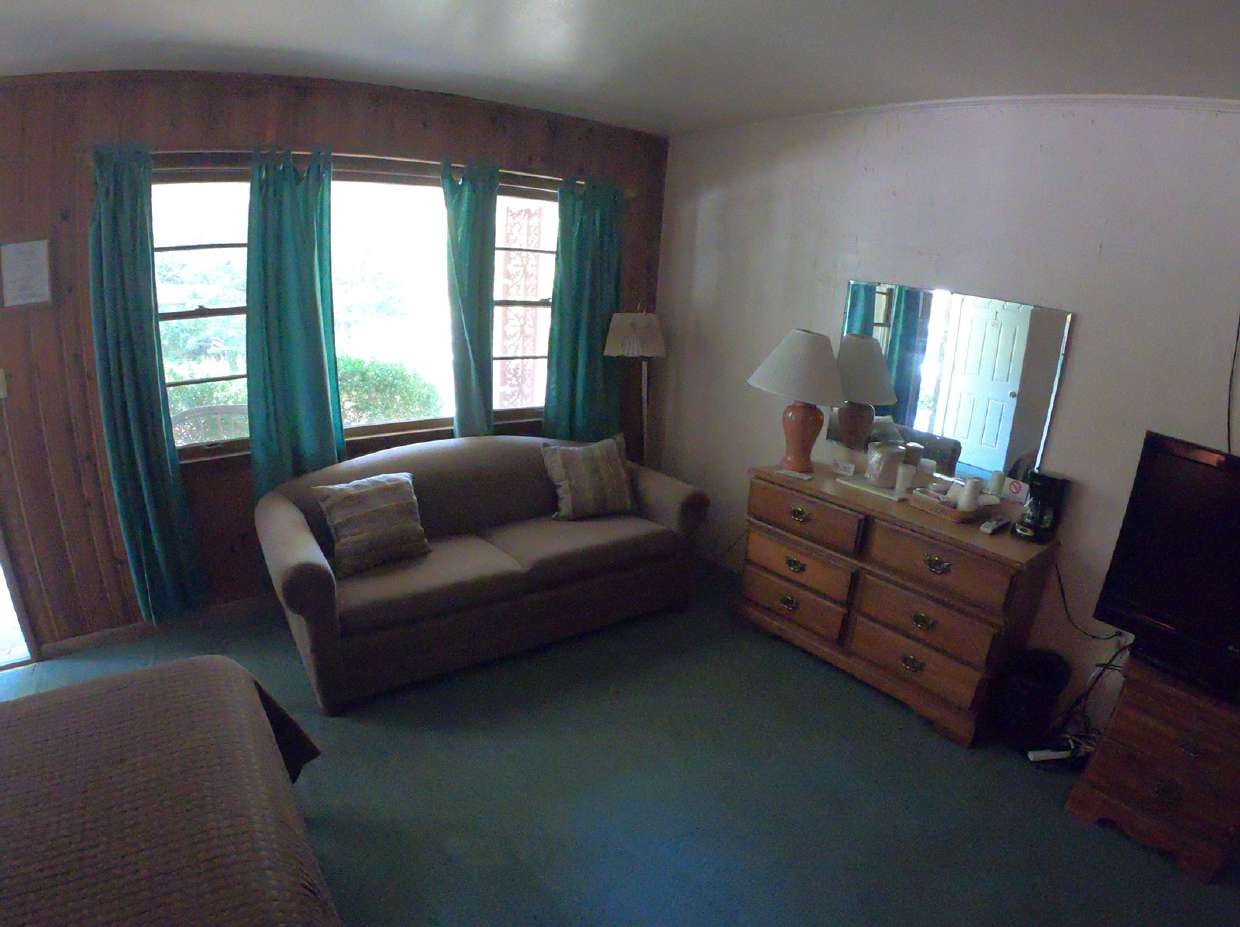 Living area with sofa, teal curtains and dresser